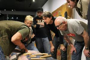 Xwalacktun leads a carving lesson as participants in the veterans tribute-pole project observe. Photo: YOLANDE COLE