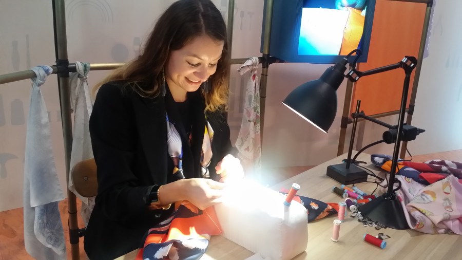 The silk roller meticulously adds the finishing touches with silk thread to every scarf.