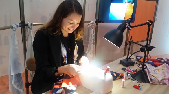 The silk roller meticulously adds the finishing touches with silk thread to every scarf.